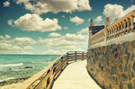Paseo marítimo y muro de piedra junto al Sendero Litoral de Mijas, con barandilla, playa y mar abierto.