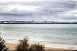 Playa de Rota con vistas al mar y al perfil urbano de la costa gaditana bajo cielo nublado.
