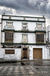 Fachada blanca con balcones en el centro histórico de Rota, bajo un cielo nublado.
