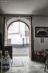 Entrada interior con arco hacia una calle de Rota, con luz natural y ambiente tradicional.