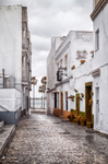 Calle empedrada de Rota con casas blancas, torre al fondo y ambiente histórico gaditano.