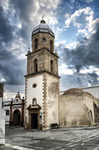 Iglesia o torre histórica de Rota, Cádiz, fotografiada desde una plaza con cielo dramático.