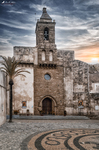 Iglesia histórica de Rota con torre de piedra, fachada antigua y cielo nublado al atardecer.