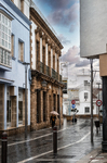 Calle del centro histórico de Rota con casas de colores suaves y torre al fondo.
