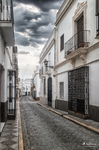 Calle larga y estrecha del casco antiguo de Rota, con fachadas blancas y balcones.