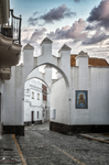 Arco blanco en una calle de Rota, con azulejo decorativo y arquitectura tradicional.