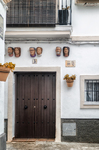 Fachada blanca de Rota con puerta de madera, macetas de flores y decoración tradicional.