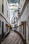 Calle estrecha de Rota con fachadas blancas, balcones y perspectiva hacia el casco antiguo.
