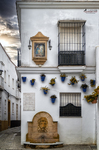 Fuente decorativa en una pared blanca de Rota, con azulejos, macetas y detalles tradicionales.