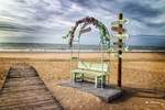 Decoración junto a la playa de Rota, con arco colorido, arena y mar Atlántico al fondo.