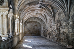 Pasillo abovedado de claustro en el norte de España, con columnas de piedra y ambiente monumental.
