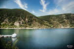 Embalse o ría interior del norte de España, con barca blanca, montañas verdes y cielo azul.