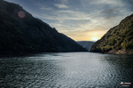 Río encajado entre montañas al atardecer en el norte de España, con luz suave sobre el agua.