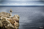 Cruz sobre una roca frente al mar en la costa del norte de España, con horizonte atlántico.