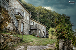 Casa antigua de piedra en entorno rural del norte de España, rodeada de vegetación y montaña.
