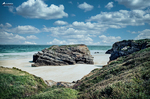 Playa de las Catedrales en Ribadeo, Lugo, con arena clara, rocas monumentales y mar Cantábrico bajo cielo azul.