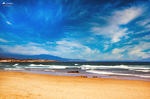 Vista amplia de la Playa de las Catedrales en Ribadeo, con arena dorada, mar Cantábrico y cielo azul intenso.