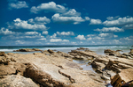 Paisaje rocoso de la Playa de las Catedrales en Lugo, con piedra tallada por el mar y cielo de nubes blancas.