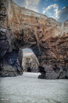 Arco natural de piedra en la Playa de las Catedrales de Ribadeo, con arena clara y roca erosionada por el mar.