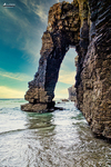 Arco de roca junto al mar en la Playa de las Catedrales, con reflejos del agua y luz suave en la costa de Lugo.