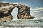 Formación rocosa con arco natural en la Playa de las Catedrales, rodeada por el oleaje del Cantábrico.