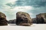 Rocas aisladas sobre la arena en la Playa de las Catedrales, con acantilados y luz clara de Galicia.