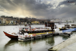 Barco rabelo en el río Duero, con la ciudad de Oporto al fondo y cielo de atardecer.