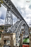 Puente Don Luis I de Oporto visto desde la ribera del Duero, con estructura metálica y edificios al fondo.