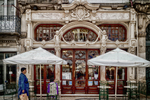 Fachada ornamentada de café histórico en Oporto, con terrazas exteriores y arquitectura elegante.