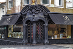 Entrada decorativa de comercio antiguo en Oporto, con fachada oscura, detalles ornamentales y carácter histórico.