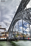 Puente Don Luis I de Oporto visto desde el río Duero, con estructura metálica y cielo nublado.