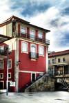 Fachada roja en el casco histórico de Chaves, con escaleras, ventanas blancas y carácter urbano portugués.