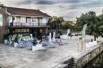 Terraza junto al río Támega en Chaves, con mesas al aire libre, edificios blancos y paisaje urbano.