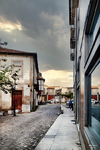 Calle empedrada de Chaves con edificios blancos, balcones y cielo nublado sobre el casco histórico.