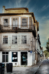 Fachada antigua de Chaves con balcones, ventanas tradicionales y comercio en planta baja.