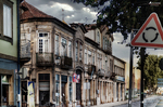 Calle de Chaves con casas tradicionales, señal de tráfico y cielo dramático.