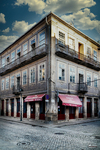 Edificio antiguo con balcones acristalados en Chaves, Portugal, sobre calle empedrada.