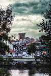 Vista de Chaves desde la ribera del Támega, con casas, árboles y cielo nublado.