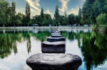 Piedras sobre el río Támega en Chaves, con reflejos del agua y vegetación en la orilla.