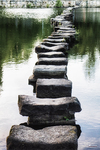 Camino de piedras sobre el río Támega en Chaves, con agua tranquila y reflejos verdes.
