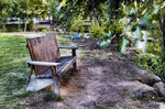 Banco de madera junto al río Támega en Chaves, rodeado de árboles y vegetación.