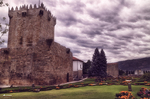 Torre de piedra de Chaves junto a jardines históricos, con cielo cubierto y ambiente medieval.