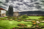 Jardín histórico de Chaves con parterres, flores y torre medieval al fondo.