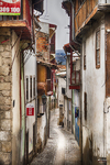 Calle estrecha de Chaves con fachadas antiguas, balcones y suelo empedrado.