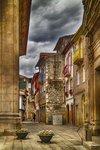 Plaza histórica de Chaves con edificios antiguos, maceteros y cielo dramático.