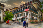 Plaza de Chaves con edificio histórico de balcones, comercios y cielo dorado.