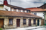 Casas tradicionales de Chaves con tejados rojos, muros de piedra y cielo nublado.