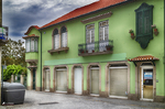 Fachada verde en Chaves, Portugal, con ventanas rojas y arquitectura urbana colorida.
