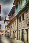 Calle del centro histórico de Chaves con balcones verdes, casas tradicionales y suelo empedrado.