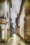 Calle estrecha de Chaves con fachadas blancas, zócalos oscuros y perspectiva profunda.